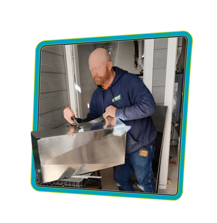 Greens Heating and AC technician cutting sheet metal to improve homeowner's indoor air quality.