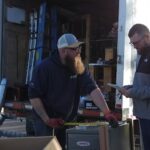 Two Greens Heating and AC technicians going over HVAC equipment specifications before an installation.