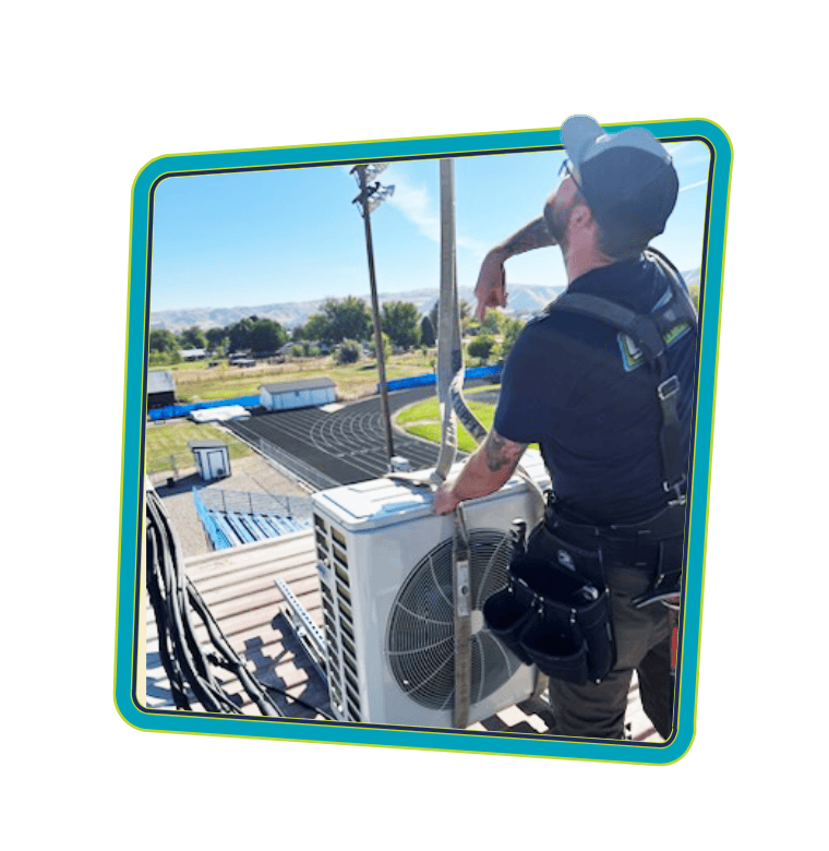 Greens' HVAC tech performing an AC installation during a cooling service call at local high school in Canyon County.